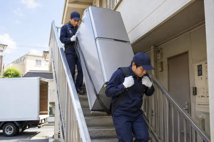 冷蔵庫を階段で運び下ろすスタッフ